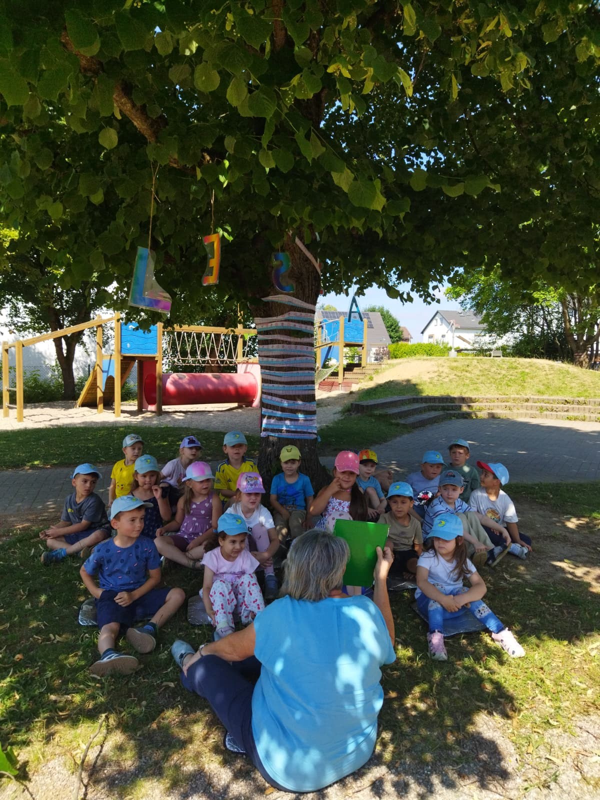 Die Kinder hören eine Geschichte unter dem Lesebaum